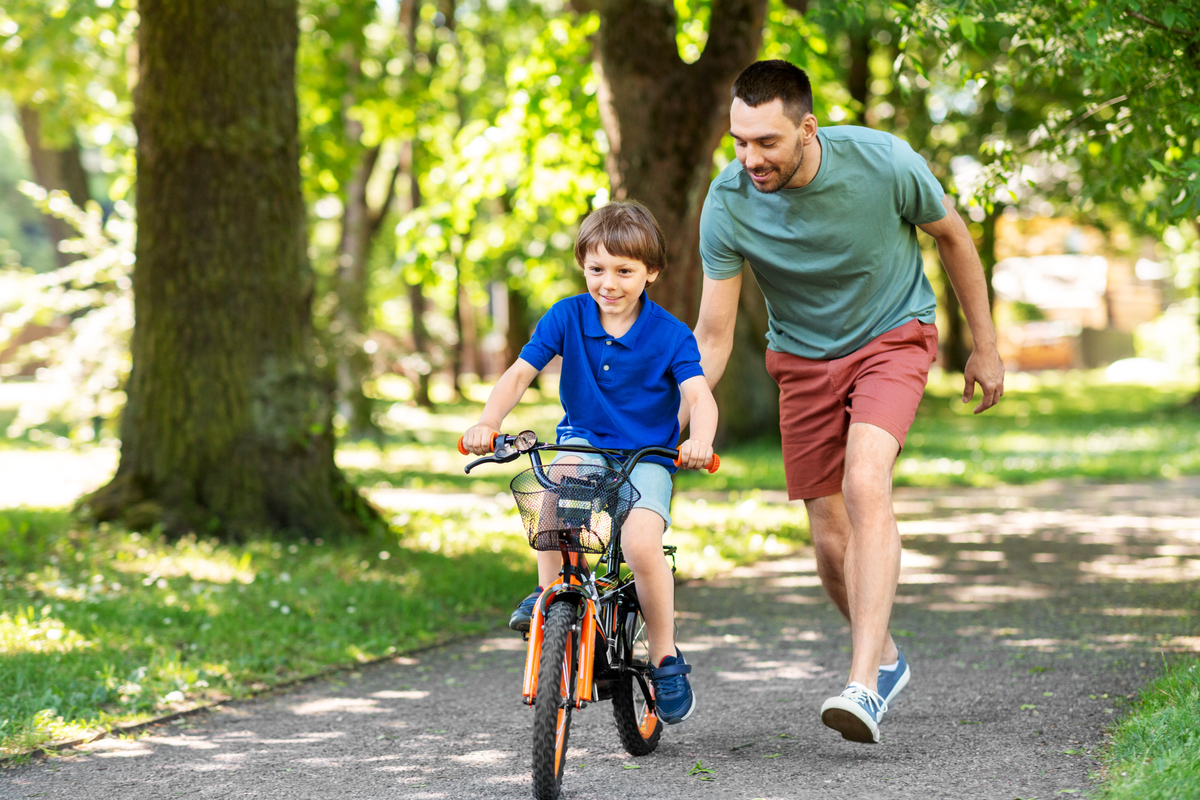 Pai ensinando o filho a andar de bicicleta no parque ao ar livre