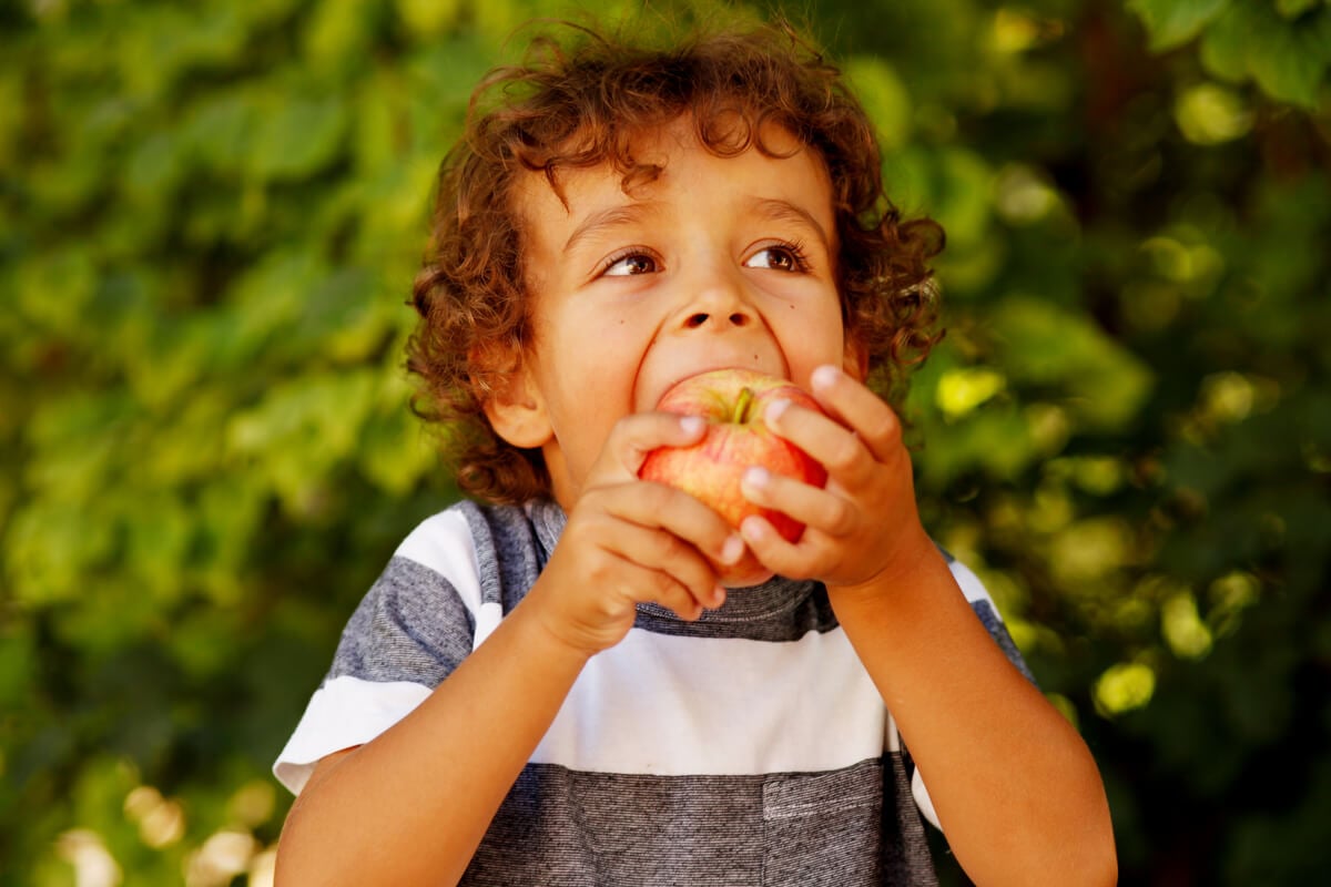 Menino comendo maçã em um parque